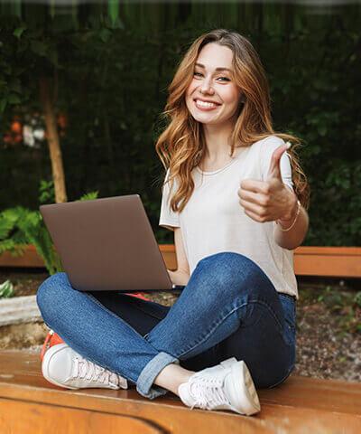 Mi primer trabajo - Joven chica sonriendo sentada mientras que utiliza en portátil