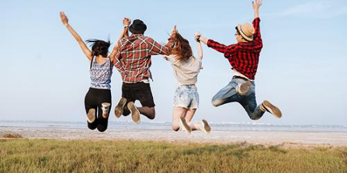Promoción Cambiar cuenta - Jóvenes felices y sonriendo saltando en el aire frente a la playa Promoción Cambiar cuenta - Jóvenes felices y sonriendo saltando en el aire frente a la playa